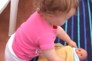 Garotinha capricha ao colocar sua boneca para dormir