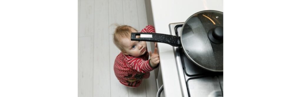 child-safety-at-home-concept-toddler-reaching-for-pan-on-the-stove-in-picture-id931131502