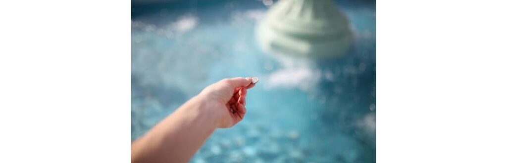 womans-hand-throwing-coin-in-wishing-fountain-picture-id809056542