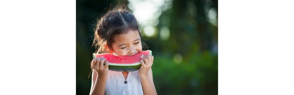 cute-asian-little-child-girl-eating-watermelon-fresh-fruit-in-the-picture-id907930534