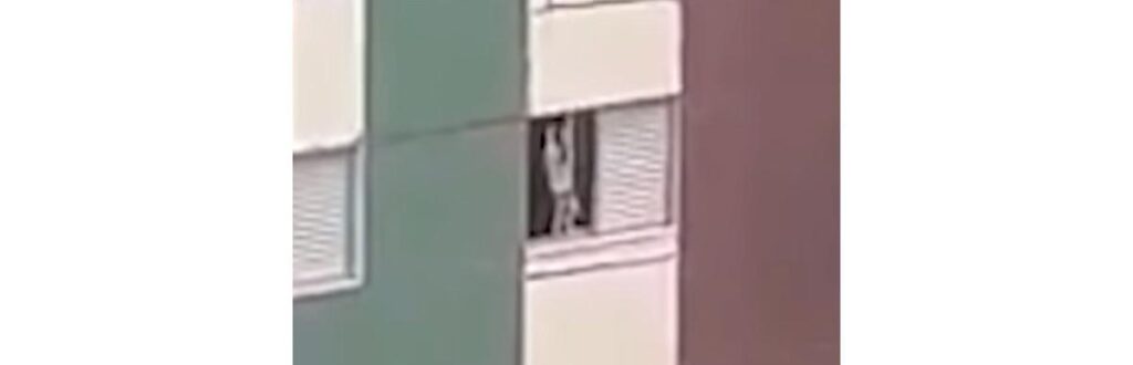 Menino se pendura em rede de proteção de prédio