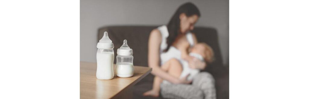 Mãe aparece ao fundo amamentando e na frente mamadeiras com leite