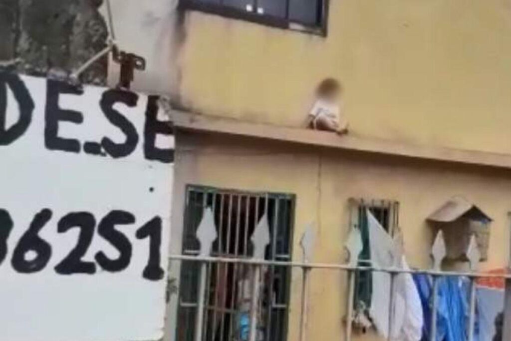 O menino estava sentado na marquise da casa