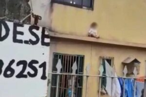 O menino estava sentado na marquise da casa