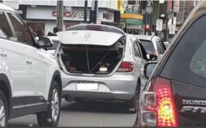 Menina é transportada no porta-malas do carro aberto em uma das principais Avenida de Poços de Calda, em Minas Gerais