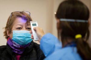Funcionários medindo a temperatura de clientes em um supermercado em Brasília