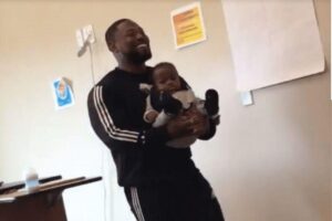 No vídeo o professor explica a matéria normalmente segurando o bebê no colo