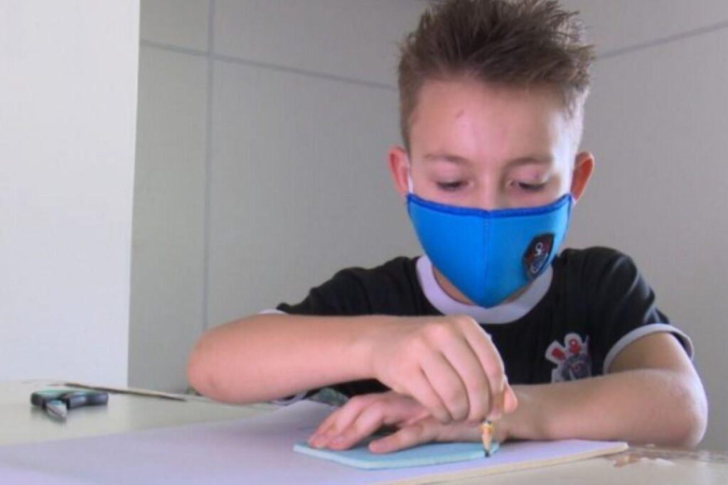 Menino faz máscaras para doar aos colegas