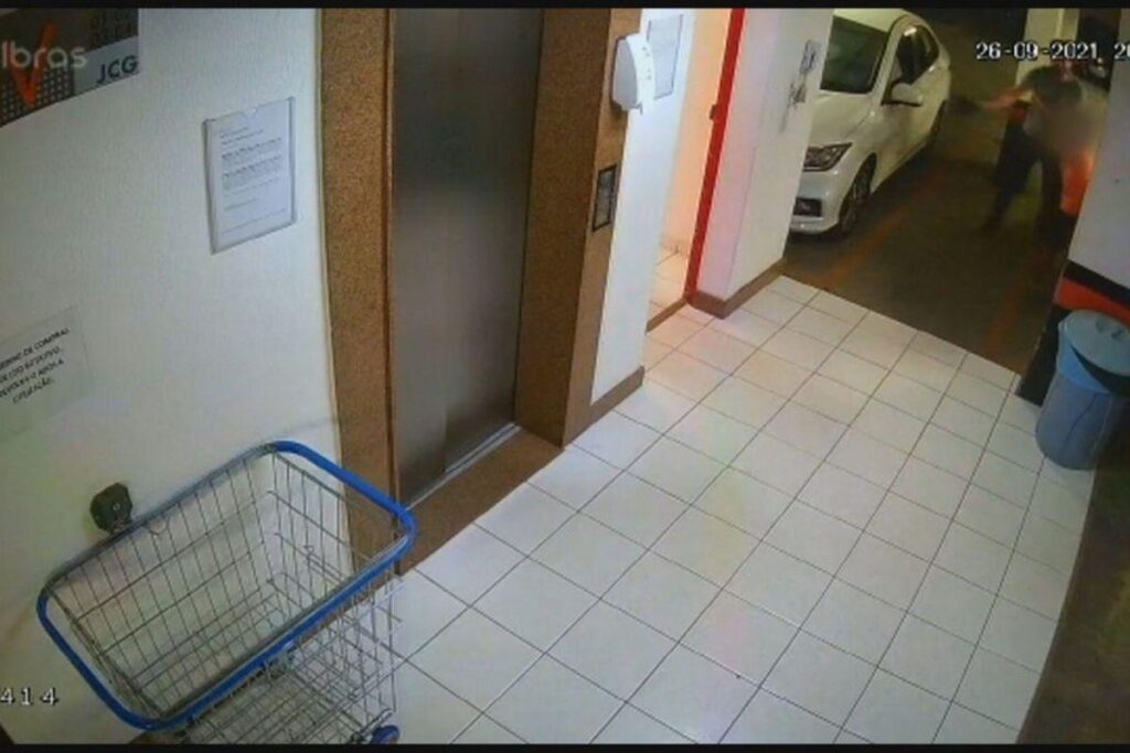 O policial aparece no canto da câmera agredindo o menino