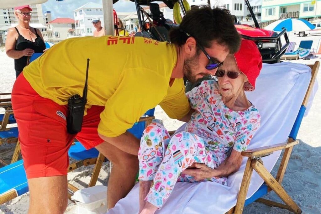 Salva-vidas ajudando senhora de 95 anos na praia