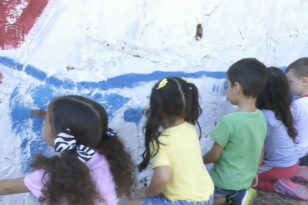 Crianças pintam bueiros para conscientizar sobre o descarte de lixo