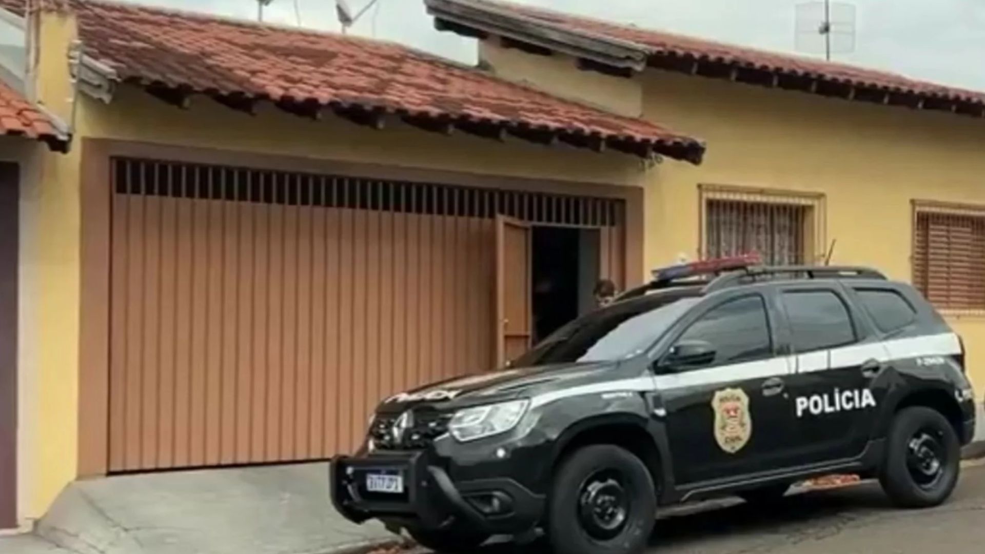 Frente de casa e carro da pol&iacute;cia