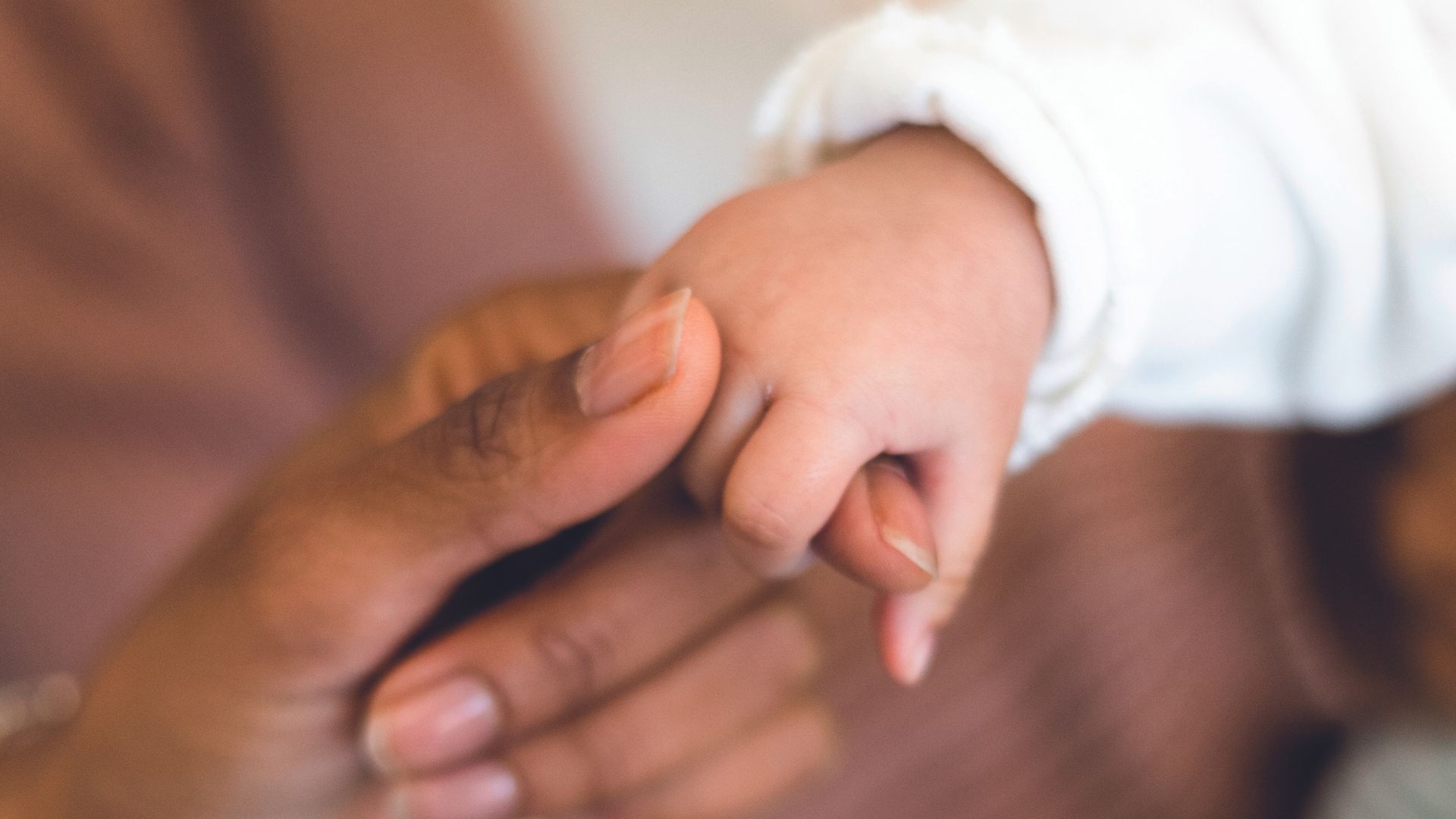 Mãe dando a mão para recém-nascido
