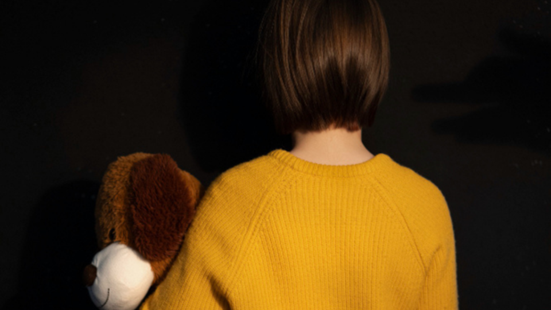 Crian&ccedil;a de costas segurando urso de pel&uacute;cia