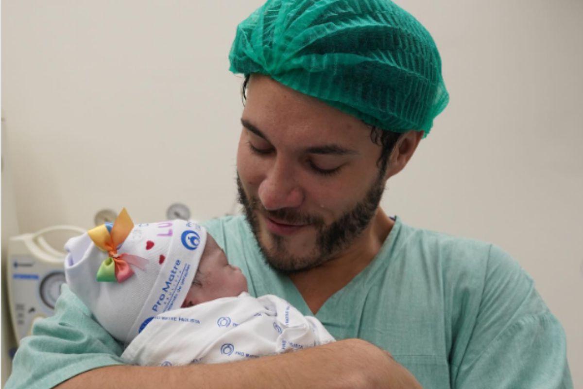 Eliezer emocionado segurando a filha no colo pela primeira vez
