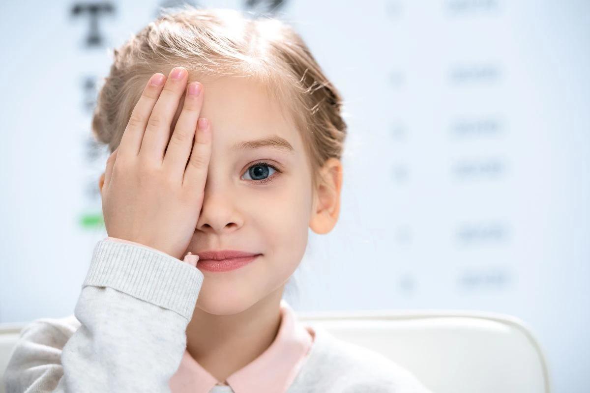 Menina tampando um olho com a mão