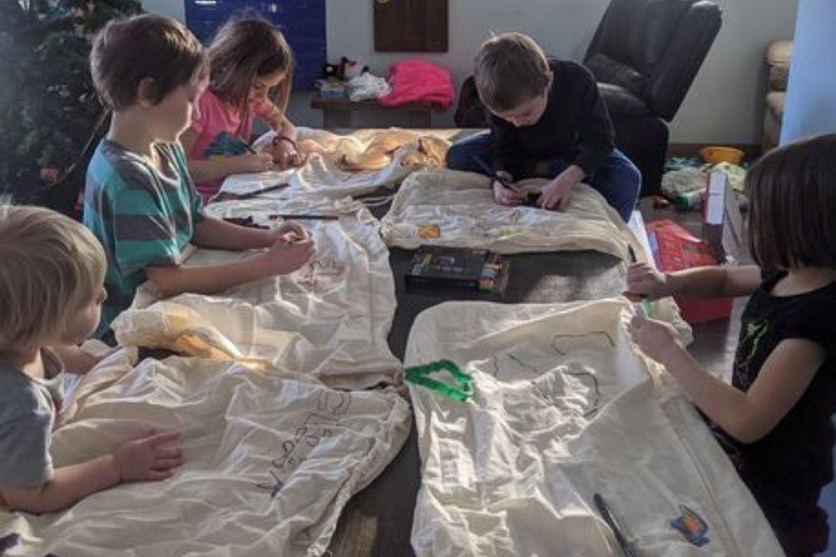 As crianças fazem a embalagem do presente de Natal