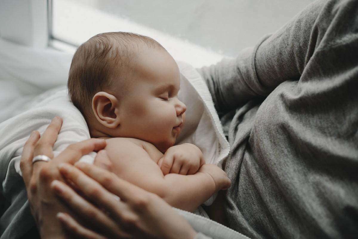 Bebê recém nascido deitado em colo de mulher