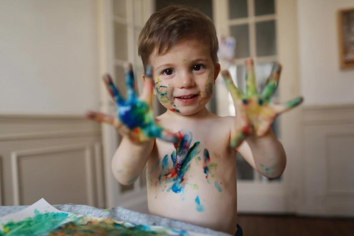 Crian&ccedil;a com as m&atilde;os cheias de tinta