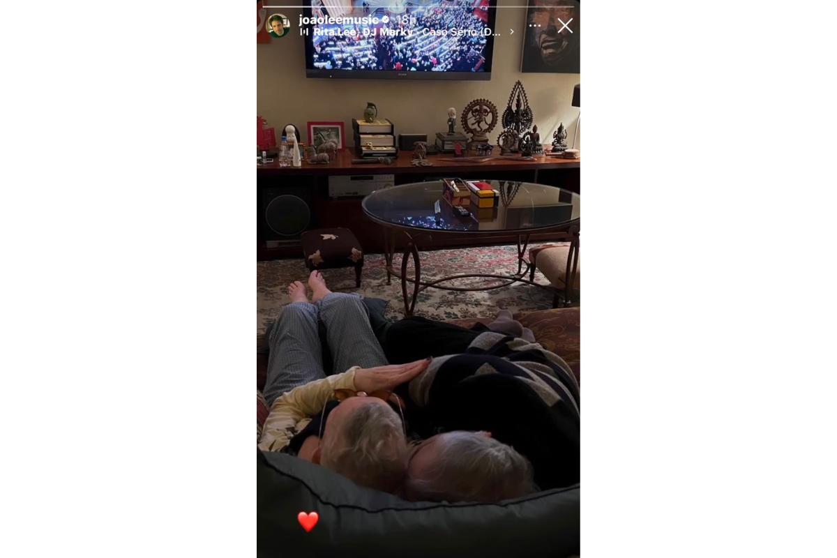 Rita Lee abraçada com o marido Roberto de Carvalho assistindo tv no sofá de casa