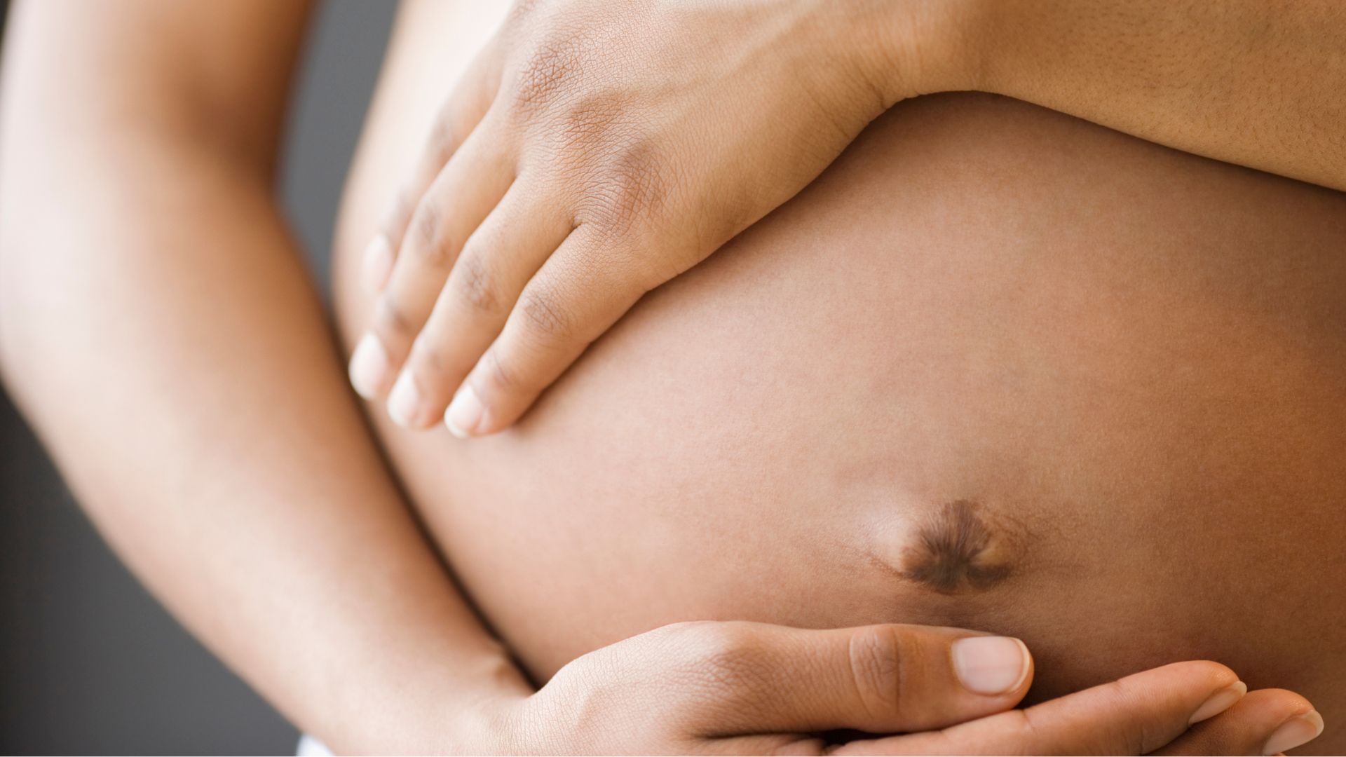 Gr&aacute;vida com as m&atilde;os na barriga