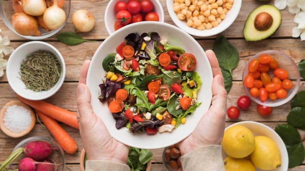 Salada variada em um fundo com diversos vegetais, representando a alimentação saudável