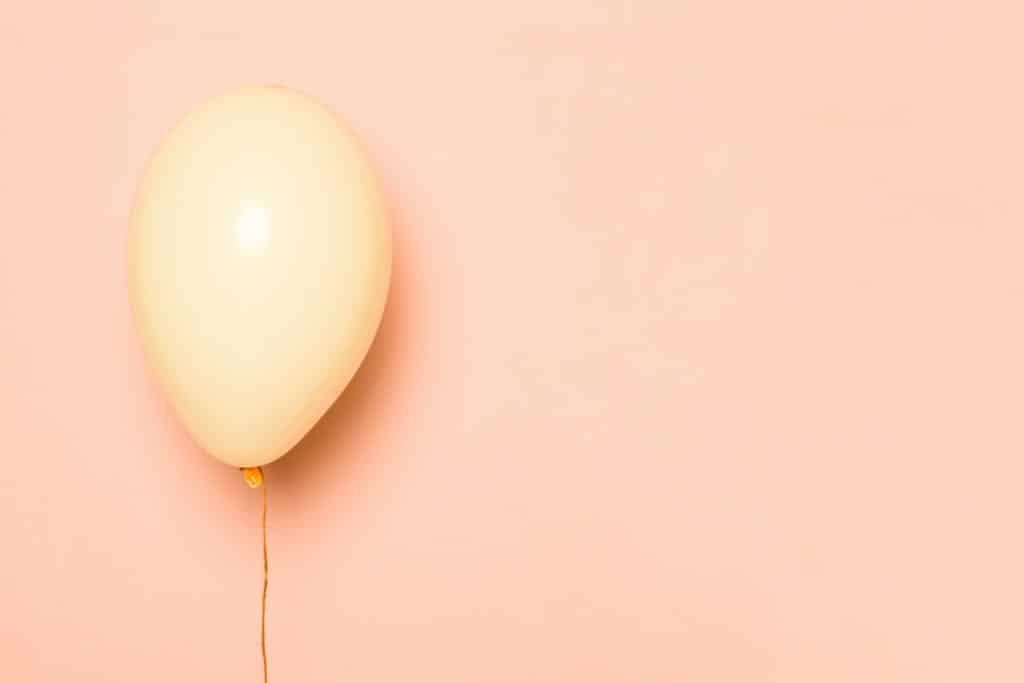 Balão rosa flutua em frente a um fundo da mesma cor representando o ganho de peso na gravidez.