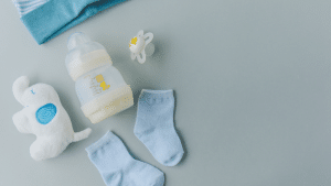 Mamadeira, chupeta, meias e brinquedo de bebê em fundo cinza