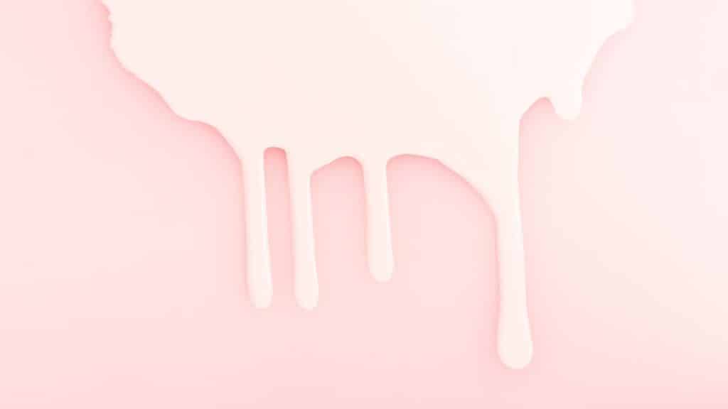 Leite derramado em um fundo rosa, representando a amamentação.