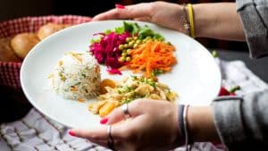 Pessoa segurando um prato com vegetais coloridos e saudáveis.