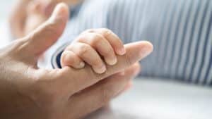 Bebê segura a mão da mãe, simbolizando a adoção.