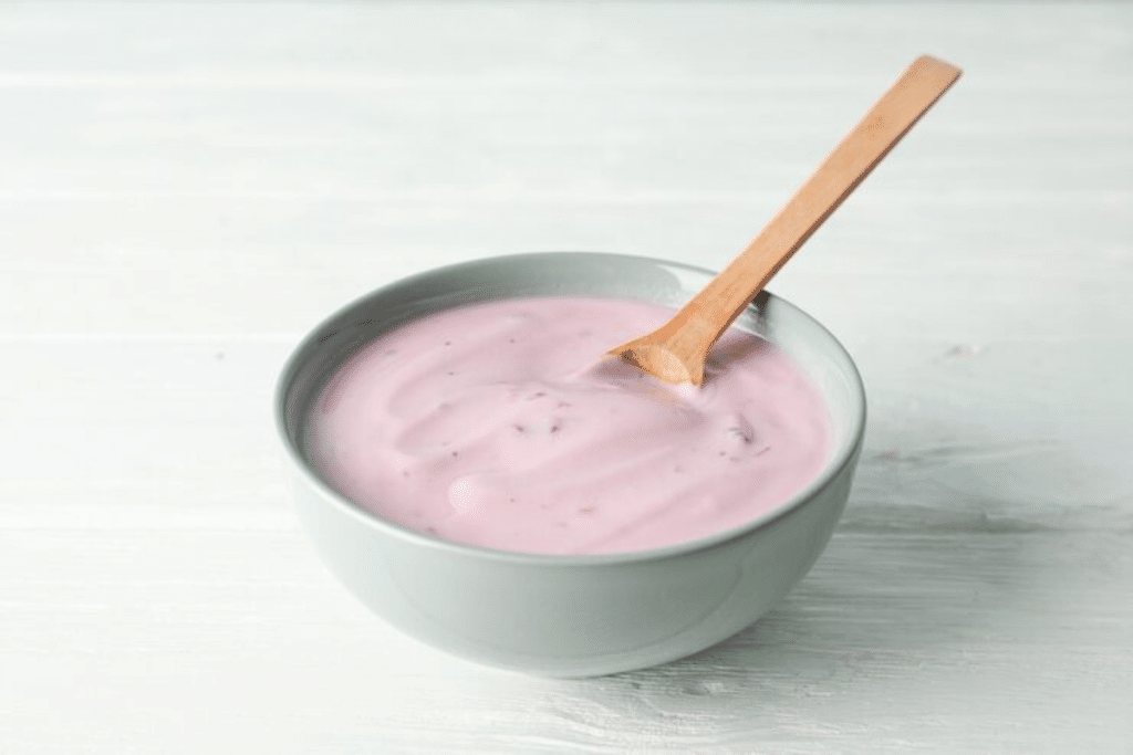 Bowl com uma colher apoiada. Dentro tem danone rosa