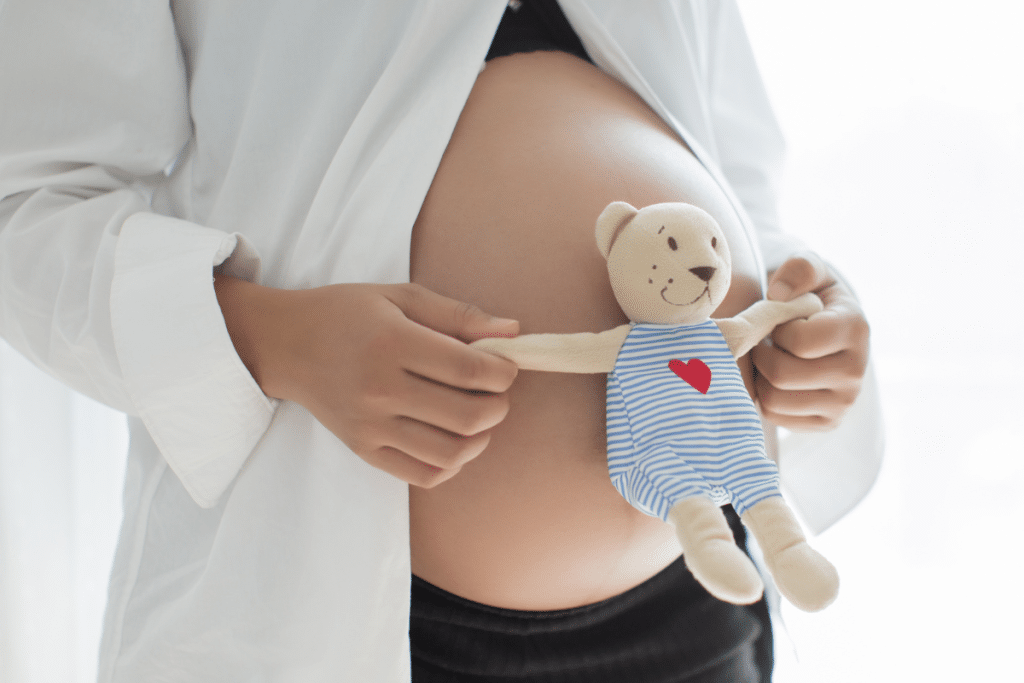 Barriga de grávida com um ursinho na frente.