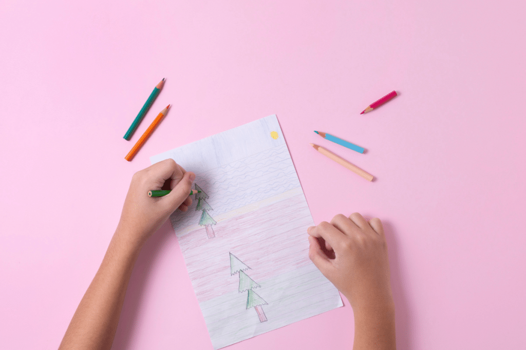 mãos de criança fazendo um desenho colorido