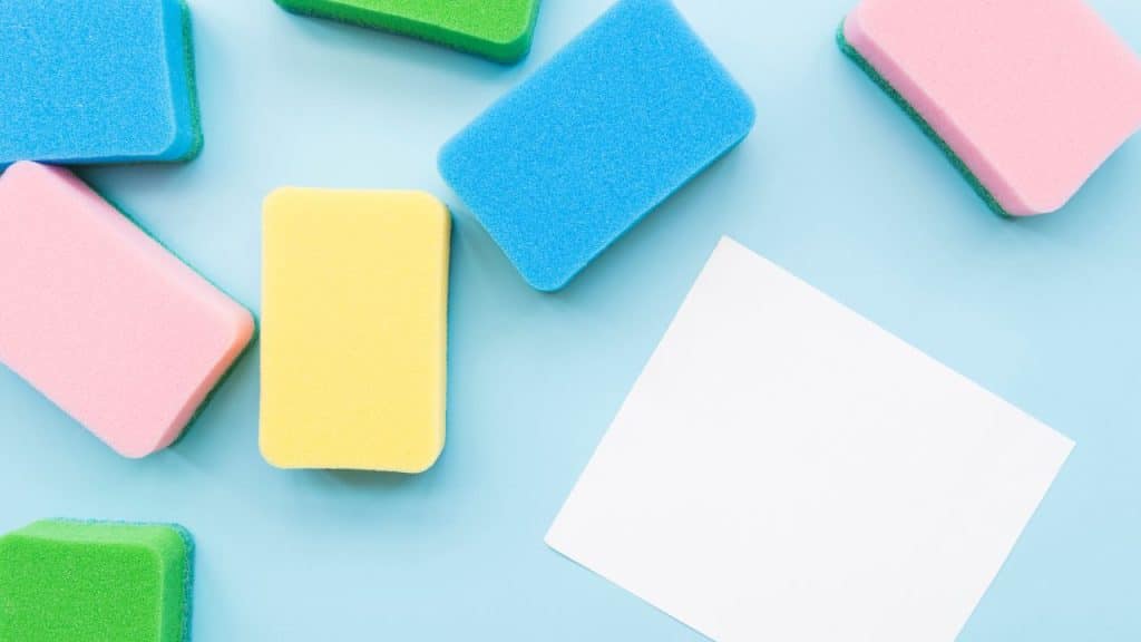 Esponjas de limpeza coloridas em um fundo azul claro.