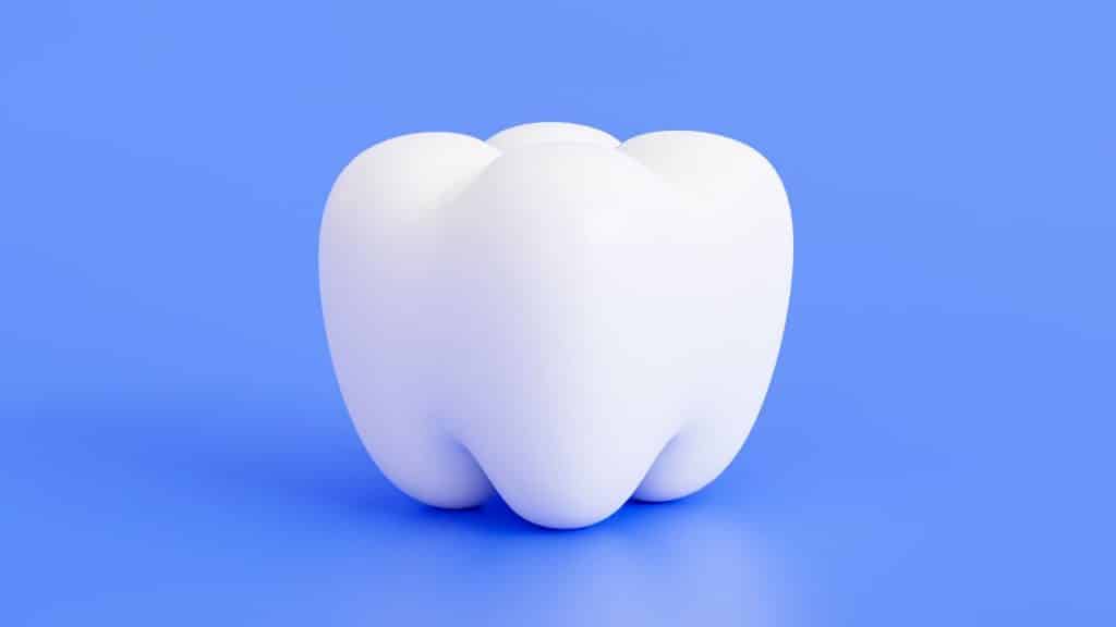 Dente arredondado em um fundo azul, representando a gengivite gravídica.