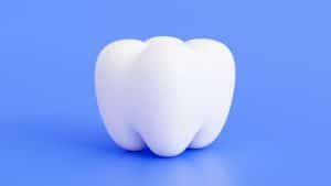 Dente arredondado em um fundo azul, representando a gengivite gravídica.