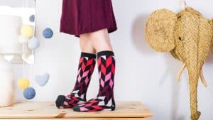 Menina com meia chamativa em cima de bancada de madeira, representando a meia maluca.