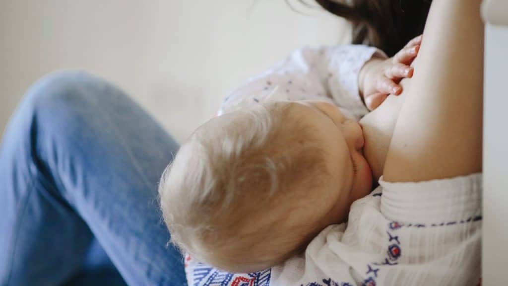 Mulher amamentando bebê com leite materno.