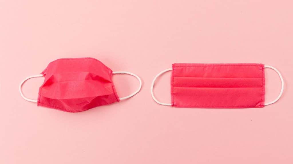 Máscaras vermelhas de resfriado em cima de um fundo rosa.