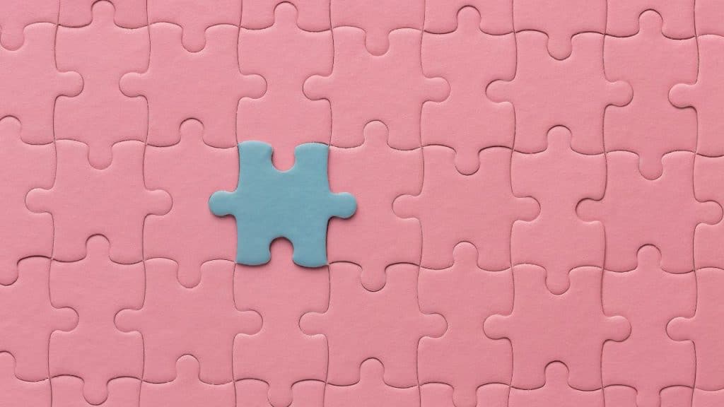 Peça azul se destacando em um quebra-cabeça rosa, representando a brincadeira de uma criança autista.