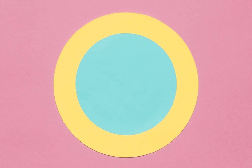 Círculos concêntricos amarelos e azuis em um fundo rosa.
