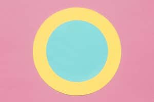 Círculos concêntricos amarelos e azuis em um fundo rosa.