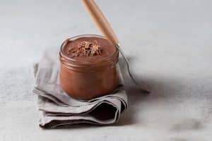 Mousse de chocolate no copo em cima de um pano e ao lado de uma colher.