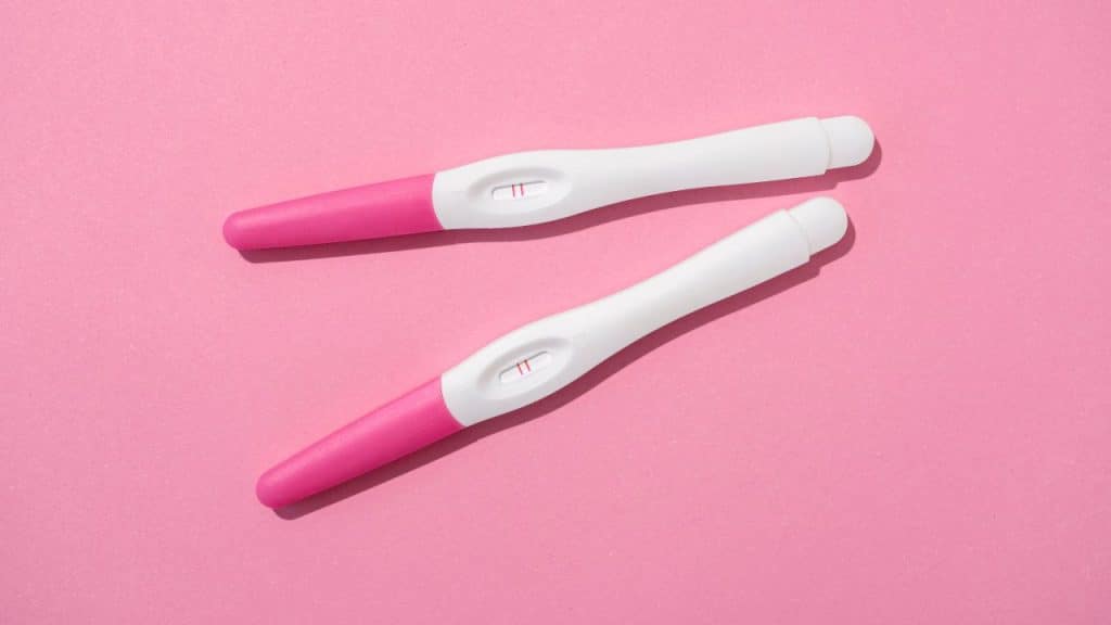 Testes de gravidez em fundo rosa, representando o início da gestação.