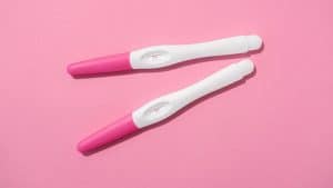 Testes de gravidez em fundo rosa, representando o início da gestação.