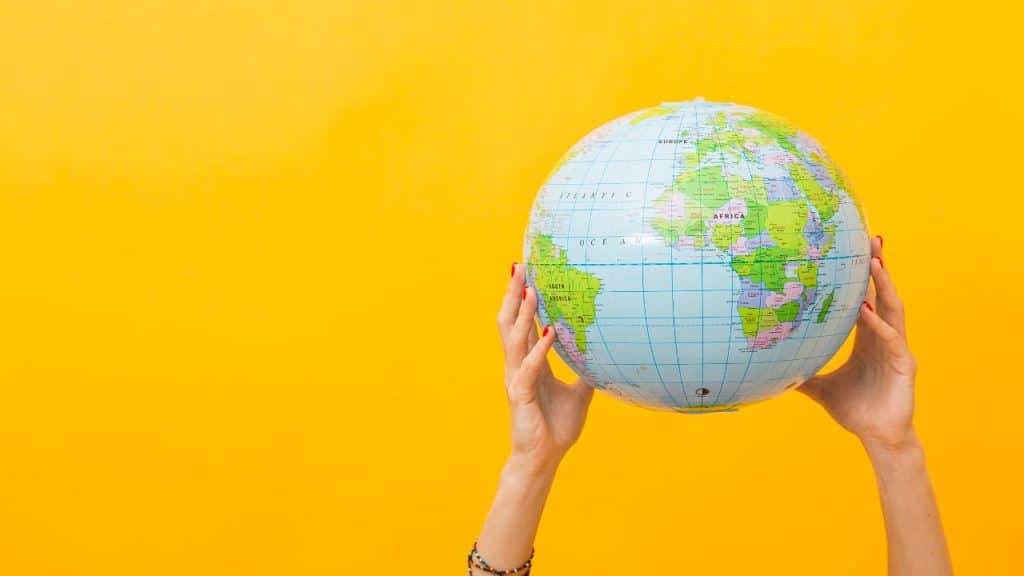 Pessoa segurando um globo em frente a um fundo amarelo, representando nomes de bebê.