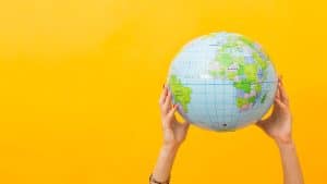 Pessoa segurando um globo em frente a um fundo amarelo, representando nomes de bebê.