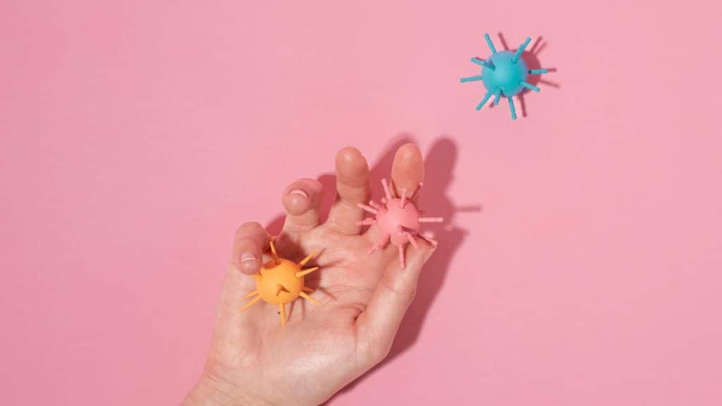 Mão segurando vírus de brinquedo, representando o sistema imunológico infantil.