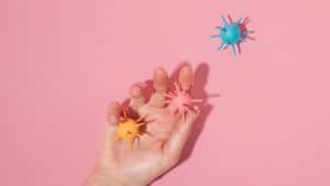 Mão segurando vírus de brinquedo, representando o sistema imunológico infantil.